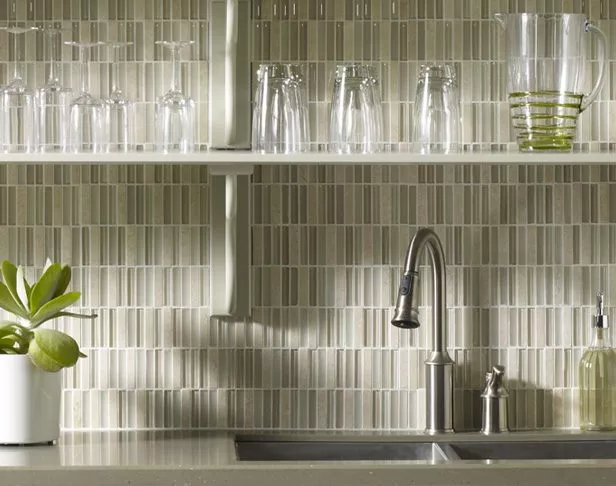Ivory glass and stone stick mosaics on a kitchen backsplash with shelves of drinking glasses