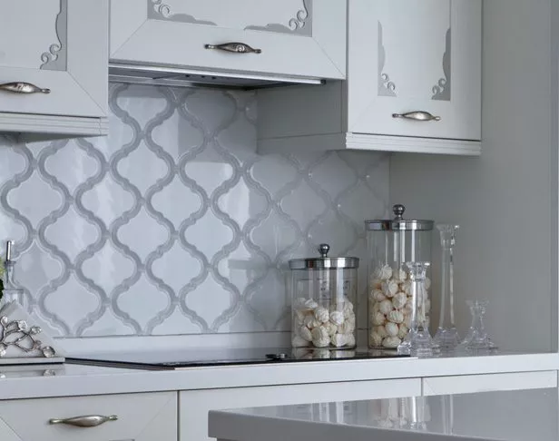white arabesque tiled kitchen backsplash with white cabinets and glass jars filled with meringue cookies