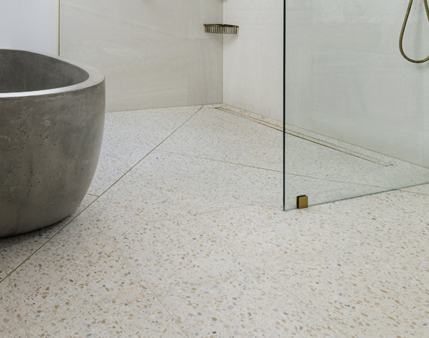 White and beige terrazzo tiled open shower floor with large concrete tub