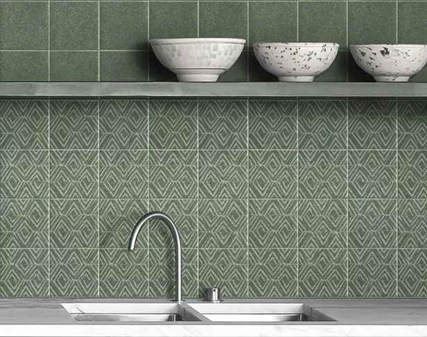 Medium green and patterned 6"x6" tiles on a kitchen wall backsplash with floating shelves and oriental bowls over a kitchen sink.