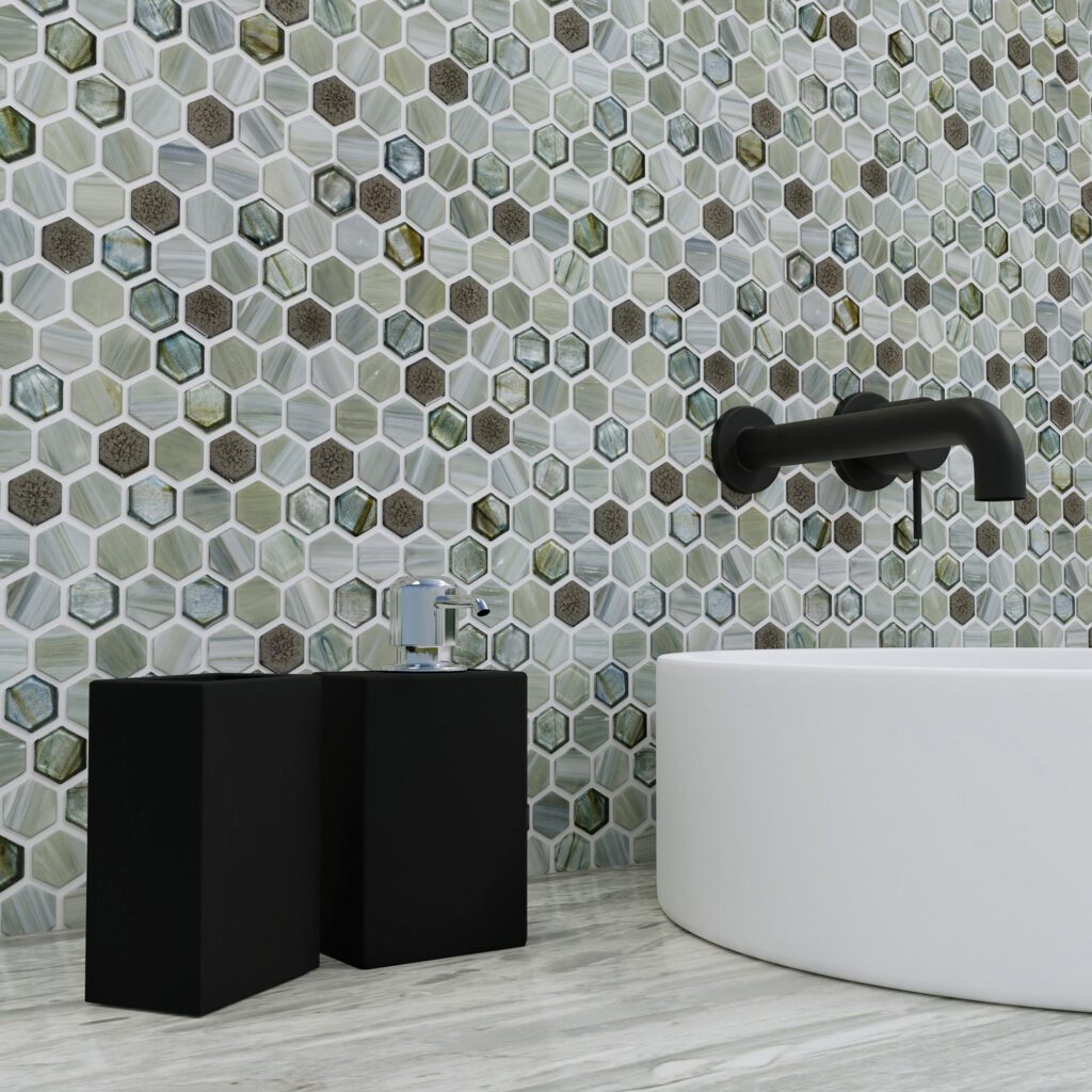 Sage Green and Brown Honeycomb shaped mosaic tiles on a wall behind a white modern vessel sink with a black wall-mounted faucet.