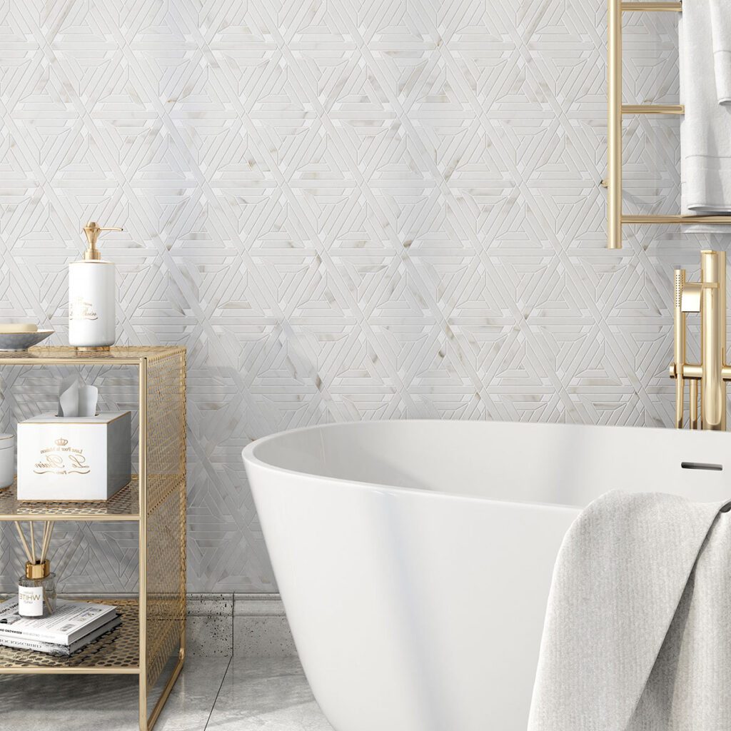 Calacatta marble and thassos marble in a triangle pattern on a bathroom wall with large white soaking tub and gold accessories