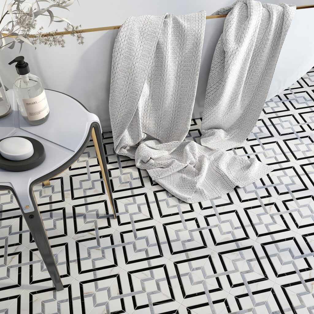 White marble with gray and black waterjet tile is a geometric pattern on a bathroom floor with soaking tub and towel
