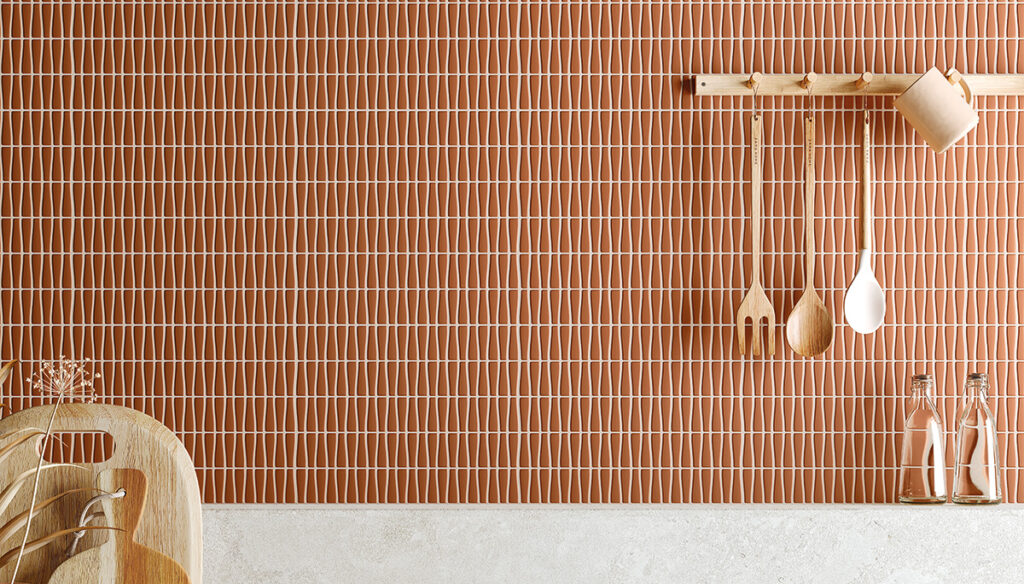 Terracotta_colored_enameled_glass_tiled_kitchen_backsplash with rack full of wooden utensils