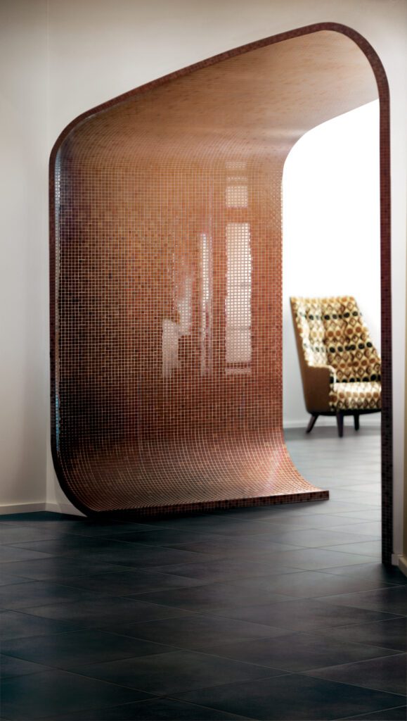 Copper colored tiny glass mosaics installed on a curved entry way.