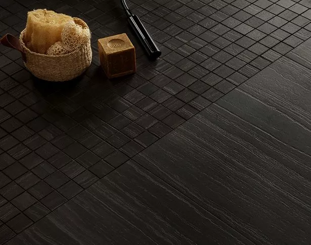 Contemporary shower floor of black and dark grey banded limestone look tile and matching mosaic tiles.