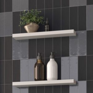 Black matte and glossy rectangular tiles with two floating shelves with plant and lotion bottles