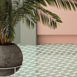 Green and white square tiles with a petal pattern on a kitchen floor with palm plant in a round concrete vase