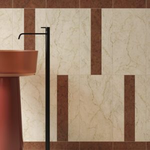 Ivory and red marble tiles on a bathroom wall installed vertically with a terracotta colored pedestal sink and black floor mount faucet