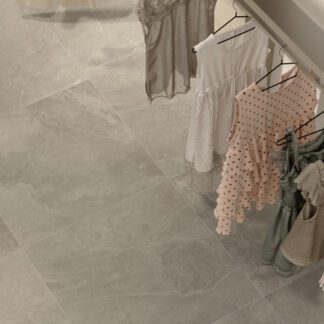 Grey stone look porcelain tile installed in a clothing shop with dresses hanging on a rack