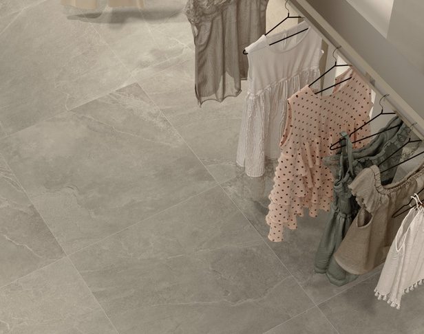 Grey stone look porcelain tile installed in a clothing shop with dresses hanging on a rack
