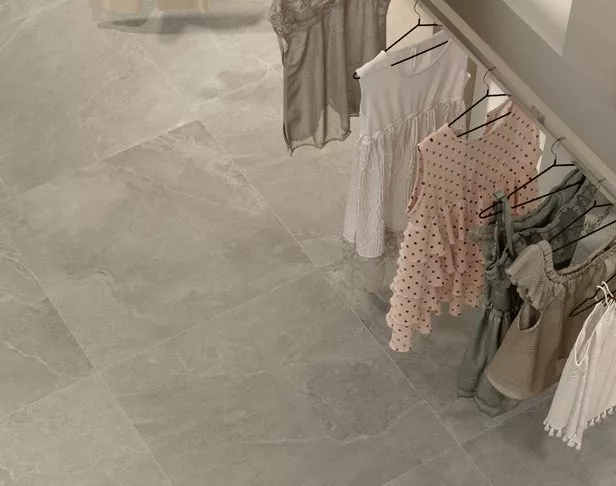 Grey stone look porcelain tile installed in a clothing shop with dresses hanging on a rack