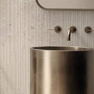 white fossilized grooved wall tile in a bathroom with brass fixtures