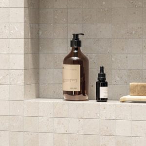 white fossilized mosaic tiled shower wall and niche with body washes and soap