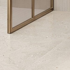 white fossilized floor tile in a shower area with brass trimmed shower enclosure