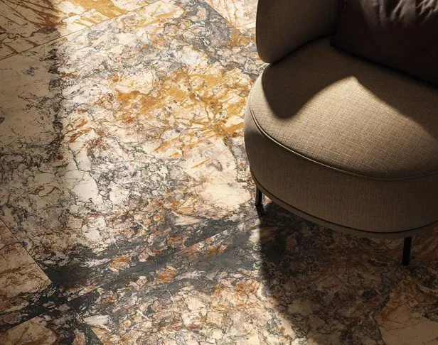 Gold and gray colored marble-look tile on a floor with brown oversized cushioned sitting chair