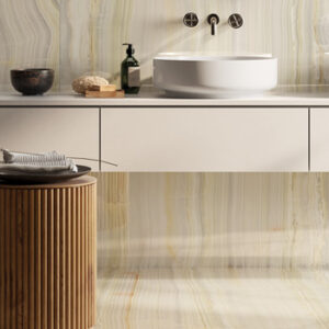 arge format pale green marble look tiled bathroom with wall mount faucet, vessel sink, and wood accent stool