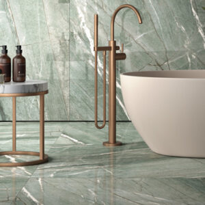 Large format pale green marble look tiled bathroom with large soaking tub and floor-mount tub filler