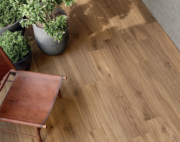 Wood-look porcelain tiled exterior space with large planters and leather folding chair