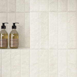 white small format tiled shower wall with niche and toiletries
