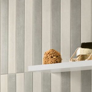 Gray and white narrow tiled wall with shelf with sea sponge