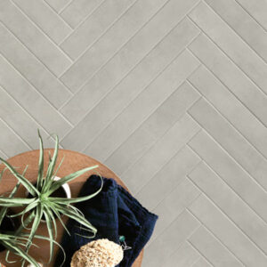 gray narrow tiles in a herringbone pattern on a floor with accent table and plants