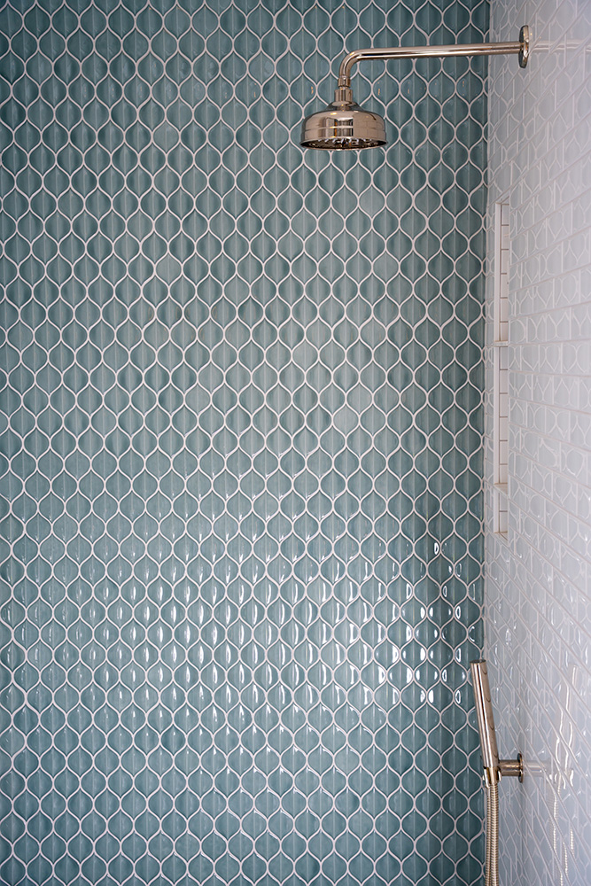 Blue 3d petal tiles on one shower wall and white subway tiles on another wall with silver fixtures