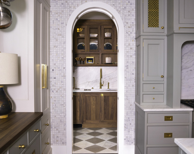 Mosaic tiled archway into a pantry with dark wood cabinets and white and brown checkerboard floor