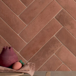 glossy terracotta colored small format tile wall in a herringbone pattern