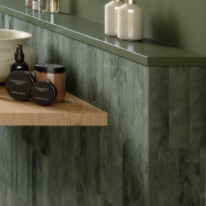 glossy green small format tiled half wall with shelf of toiletries