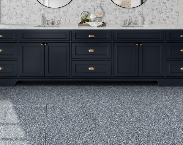 Black and white terrazzo tiled bathroom floor with large dark gray sink vanity with gold handles